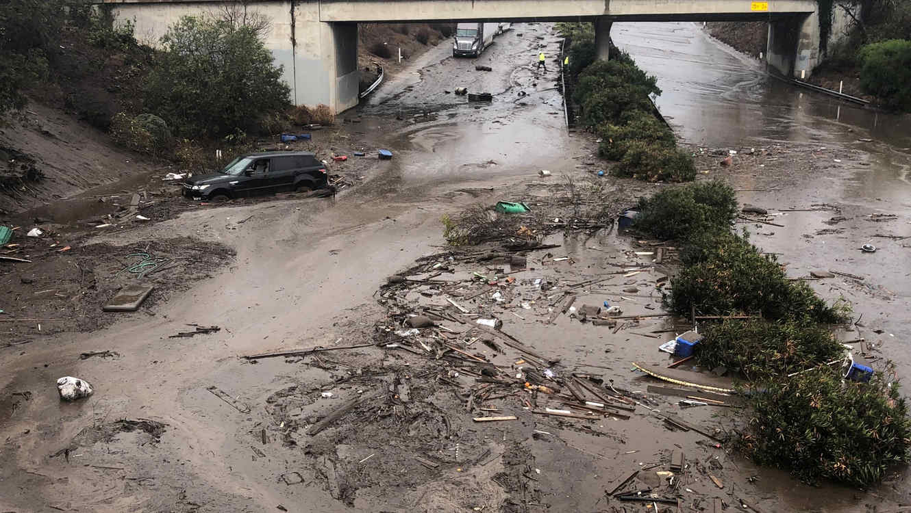 Carros varados y abandonados en una carretera inundada en Montecito, California