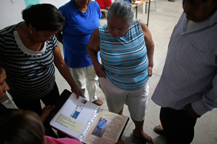 1 de diciembre de 2015, familiares de personas desaparecidas repasan un archivador lleno de imágenes e información sobre personas desaparecidas, en un sótano de la iglesia de San Gerardo en Iguala.