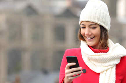 Mujer con atuendo invernal sonríe con Smartphone