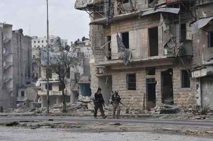 Soldados caminando entre los escombros en Alepo
