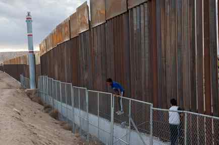 Dos jóvenes en el muro fronterizo entre México y EEUU