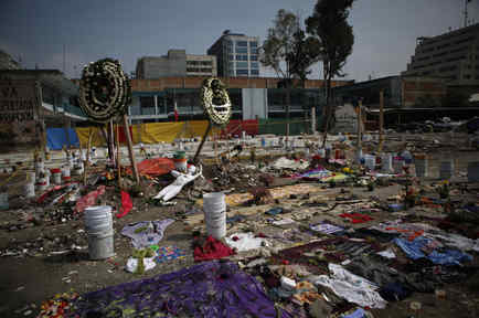 Coronas de flores, ropa, materiales de costura y un maniquí se organizan en un monumento que incluye consignas de protesta en el sitio de una fábrica textil que se derrumbó en el terremoto de 7,1 grados de la semana pasada en la Ciudad de México