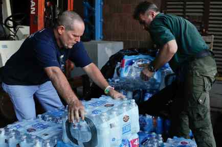 Dos hombres con agua embotellada para los damnificados del huracán María en Puerto Rico