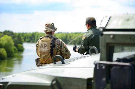 Un elemento de la Guardia Civil de Texas y un agente de la Patrulla Fronteriza discuten frente al Río Grande en la frontera con México