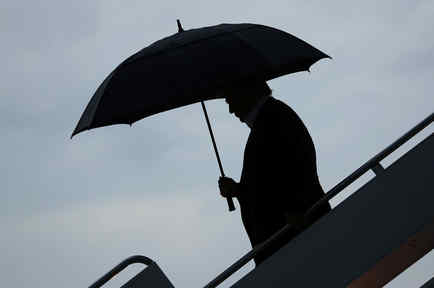 El presidente de EEUU, Donald Trump, desciende del avión presidencial con un paraguas