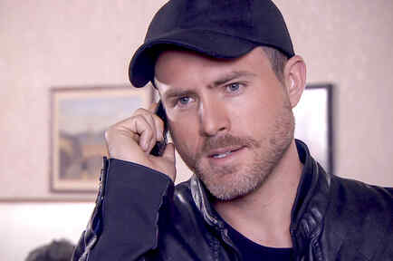 Erik Hayser con gorra negra hablando por teléfono en Los Miserables 
