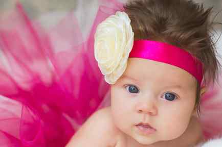 Bebé con flor en la cabeza y cinta rosa