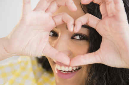 Mujer hispana formando un corazón con las manos sobre su rostro