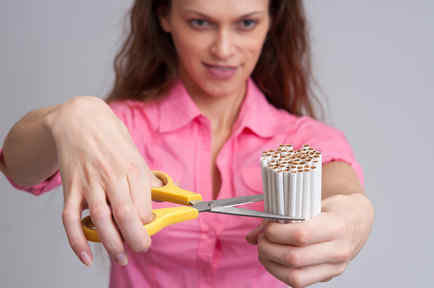 Mujer corta puñado de cigarrillos con tijera