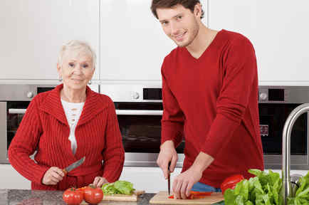 Hombre joven cocinando con anciana