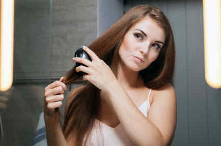 Mujer cepillándose el cabello frente al espejo.