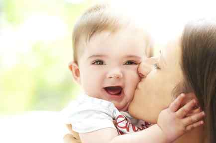 Mother kissing smiling boy toddler on the cheek