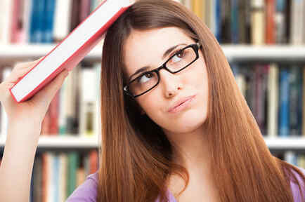 Retrato de una estudiante distraída con un libro en la biblioteca