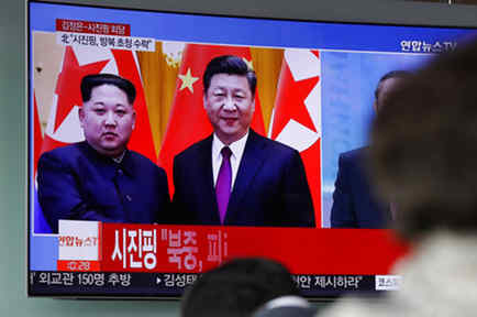 Varias personas ven un programa de televisión que informa sobre el encuentro entre los líderes norcoreano y chino en Pekín. 