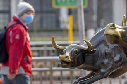 Un hombre utilizando una máscara frente a la escultura de unos toros en Beijing, China.