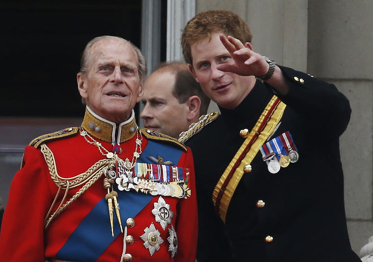 En esta foto del 14 de junio de 2014, el príncipe Harry de Inglaterra habla con su abuelo, el príncipe Philip, en el balcón del Palacio de Buckingham durante el desfile del Trooping The Colour en Londres.