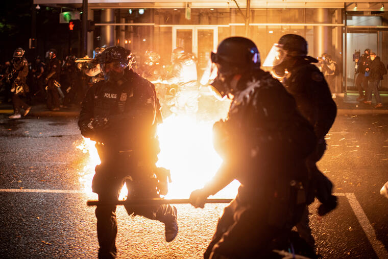 Portland police officers evade a molotov cocktail during unrest that followed the grand jury decision in Portland