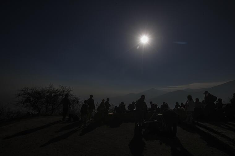 Cientos de personas acuden este martes a lo alto del Cerro San Cristóbal para observar el eclipse solar, en Santiago (Chile). 