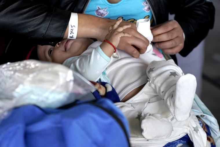 Una mujer viste a un bebé en un centro de descanso para migrantes en Brownsville