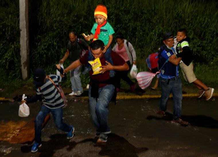 Migrantes comienzan su viaje hacia Estados Unidos bajo la lluvia desde una estación de autobuses de San Pedro Sula, Honduras, el lunes 14 de enero de 2019.