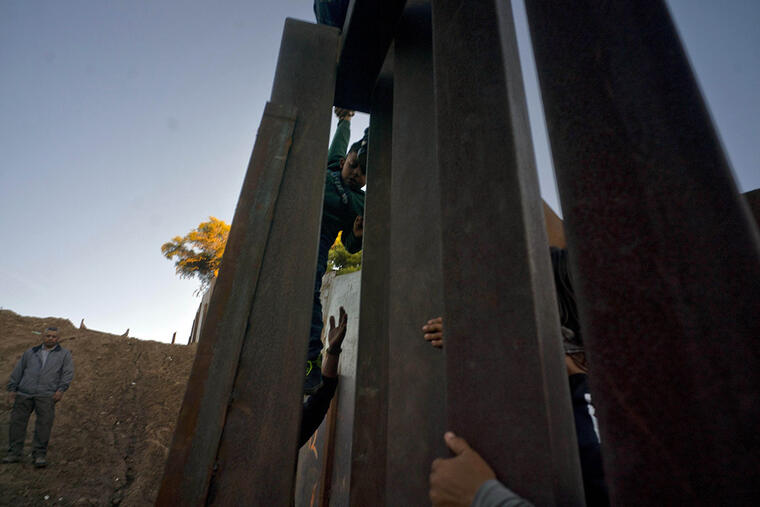 Migrantes hondureños cruzan el muro desde Tijuana hacia Estados Unidos. 