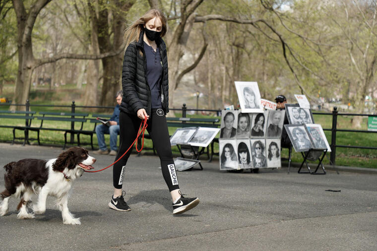 Una mujer con mascarilla pasea a su perro en Central Park