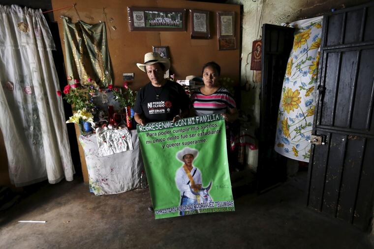 Clemente Rodríguez y María Telumbre posan con una pancarta en honor a su hijo Christian Alfonso, en su casa de Tixtla, Guerrero, en 2015