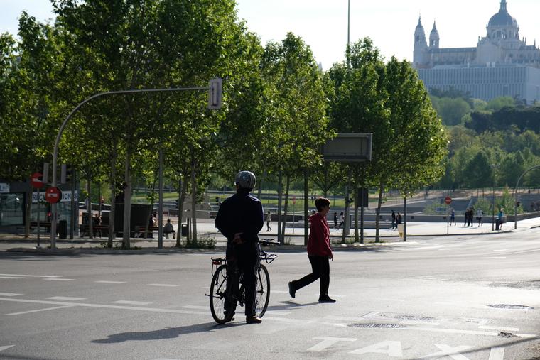 Un ciclista aguarda el vía libre de un semáforo para seguir con su marcha en Madrid. En el fondo, la catedral de la capital de España. 