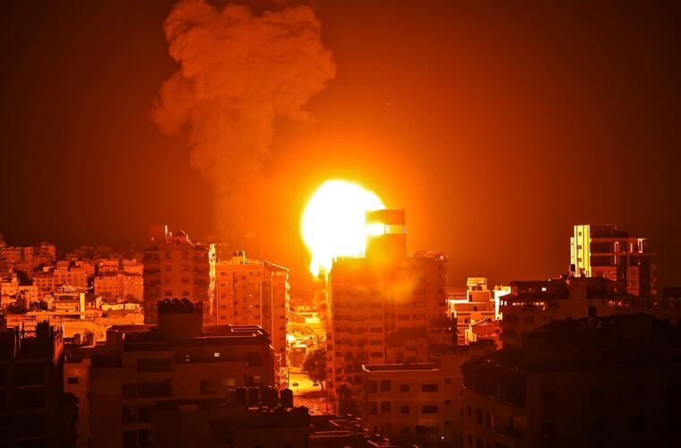 Una bola de fuego y una columna de humo se elevan sobre los edificios de la ciudad de Gaza.
