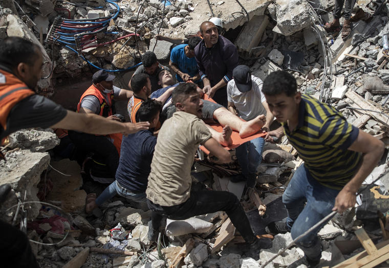 Palestinos rescatan a un superviviente de entre los escombros.