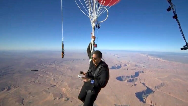 David Blaine en la mitad de su última travesía, colgando de 52 globos de helio sobre el desierto de Arizona.