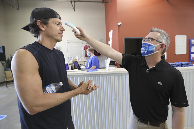 Paul Pitney, el director del gimnasio Dickson County Family YMCA, en Tennessee, e toma la temperatura a un cliente que viene a entrenar este viernes. 