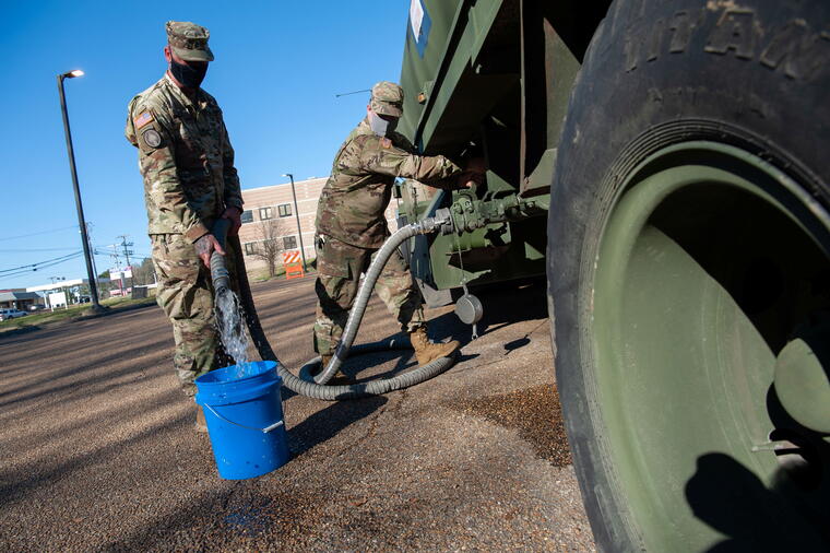 Sargentos de la Guardia Nacional llenan cubos de agua en un punto público de distribución en Jackson, Mississippi