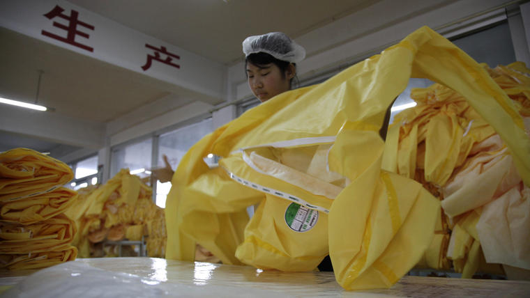 En esta imagen tomada el 30 de octubre de 2014, un trabajador chino manipula un traje que cumple con los estándares de seguridad exigidos para tratar a los pacientes con ébola, en una fábrica en la ciudad de Anqiu, en la provincia china de Shandong