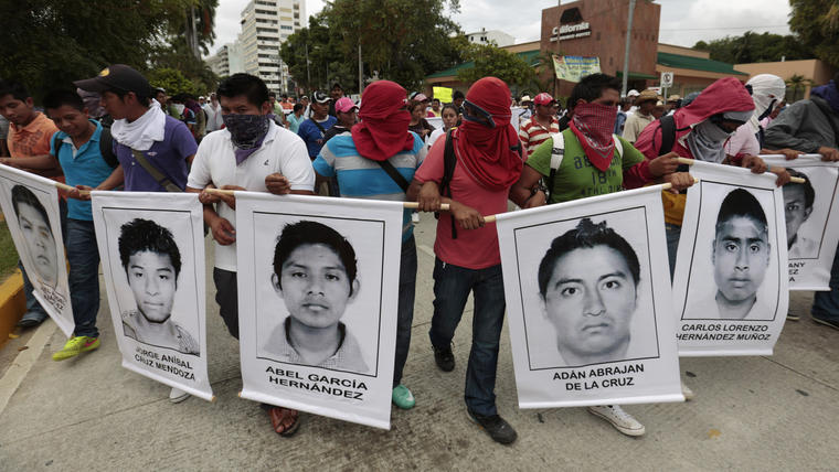 Manifestantes enmascarados marchan con las fotos de estudiantes desaparecidos y entonan cánticos para protestar contra la desaparición de 43 estudiantes de la escuela rural de maestros Isidro Burgos en Acapulco, estado de Guerrero, México, el viernes 17 de octubre de 2014. 