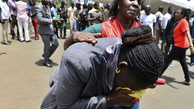 A relative is assisted by Red Cross staff as bodies of the students killed in Thursday's attack by gunmen, arrive at the Chiromo Mortuary in Nairobi