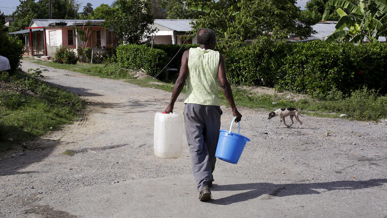 A man carries buckets of water while is searching a some of water at La Chusmita neighbourhood in Consolacion del Sur, Pinar del Rio province
