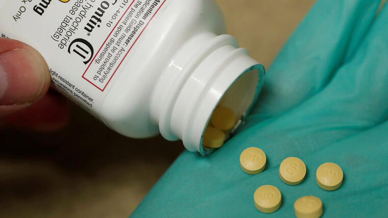 Un farmacéutico sujeta un bote de píldoras de un analgésico opiáceo 