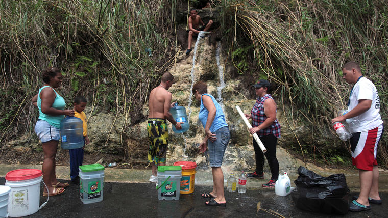 En esta foto del 17 de octubre de 2017, varias personas recogen agua de un manantial de montaña en la Corozal, Puerto Rico.