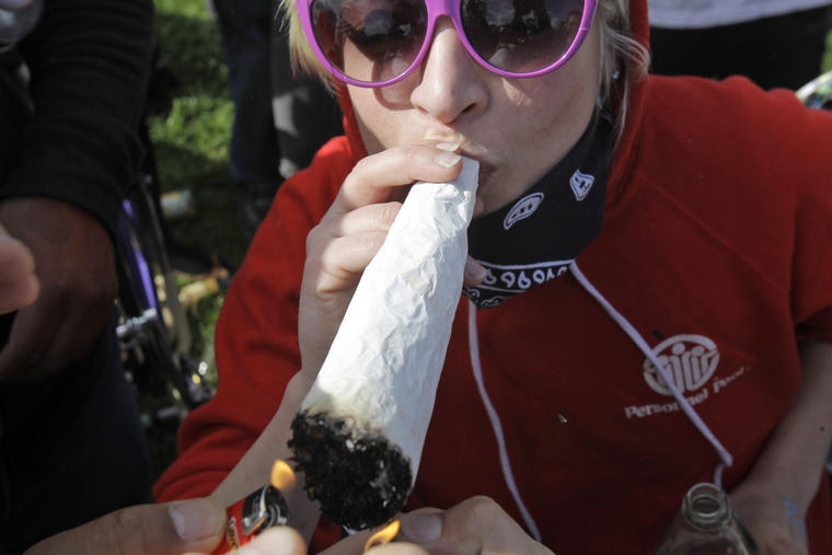 Una mujer enciende un enorme cigarro de marihuana en un parque de California.