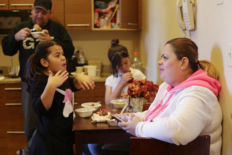 Enghie Melendez sentada junto a sus hijas Lidia, a la izquierda, Alondra, y su marido, Fernando Moyet, en la cocina de su hotel en el barrio de Brooklyn, Nueva York.