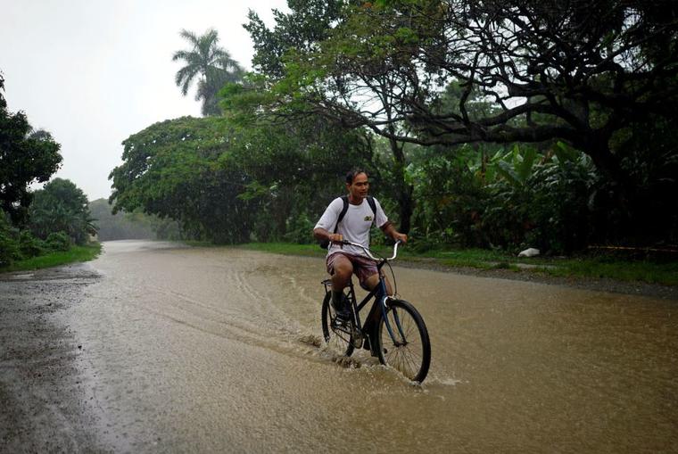 Un hombre monta una bicicleta por un camino inundado en Cuba.