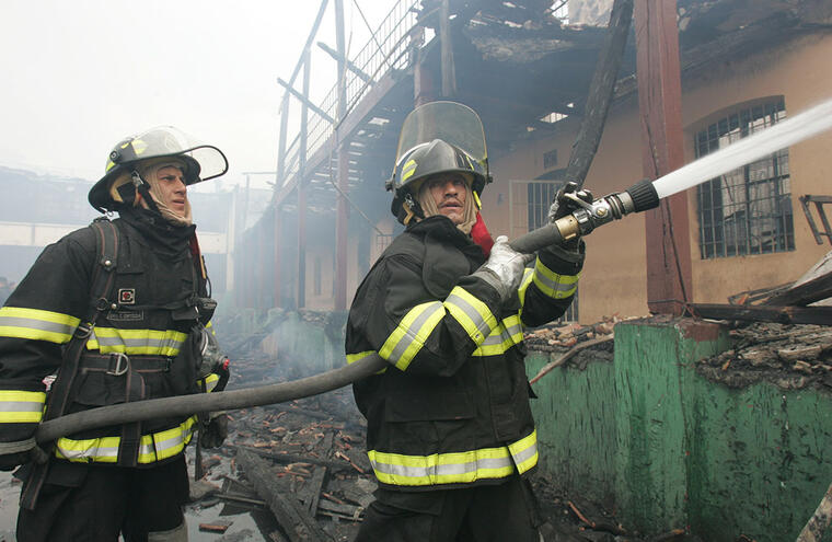 En esta imagen de archivo, dos bomberos ecuatorianos trabajan para socavar un incendio. 