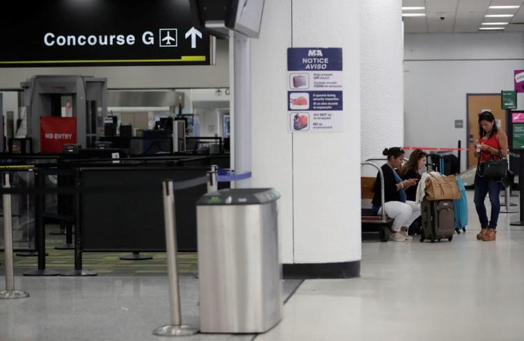 Viajeros esperan cerca de una terminal cerrada en el Aeropuerto Internacional de Miami este sábado 12 de enero de 2019.