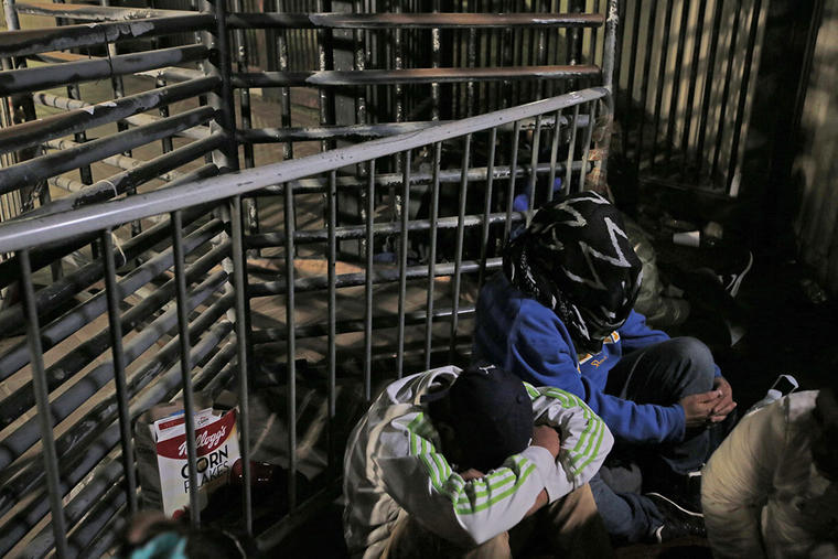 Inmigrantes centroamericanos cubren su cara mientras esperan en el puerto de entrada de Otay Mesa, en San Diego.
