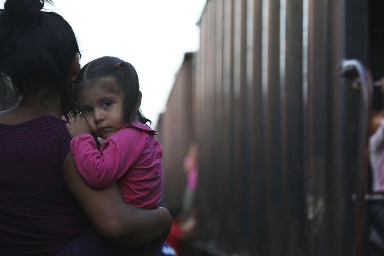 Una madre migrante y su hijita esperan un tren para atravesar México.