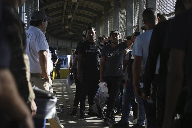 Migrantes esperan en una fila pararegresar a México y esperar sus turnos para solicitar asilo en Estados Unidos. 