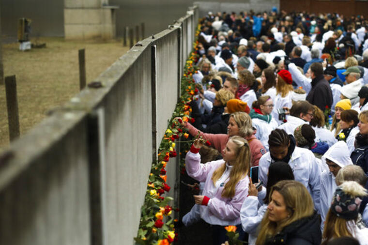 Personas dejan flores cerca de una de las partes que quedan del muro de Berlín, cuya caída ocurrió hace treinta años. 