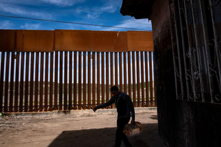 Un hombre transporta agua cerca de la valla fronteriza México-Estados Unidos en Tijuana, Estado de Baja California, México, el 28 de enero de 2019.