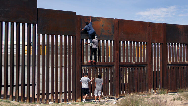 Unos jóvenes mexicanos trepan el muro en Ciudad de Juárez.